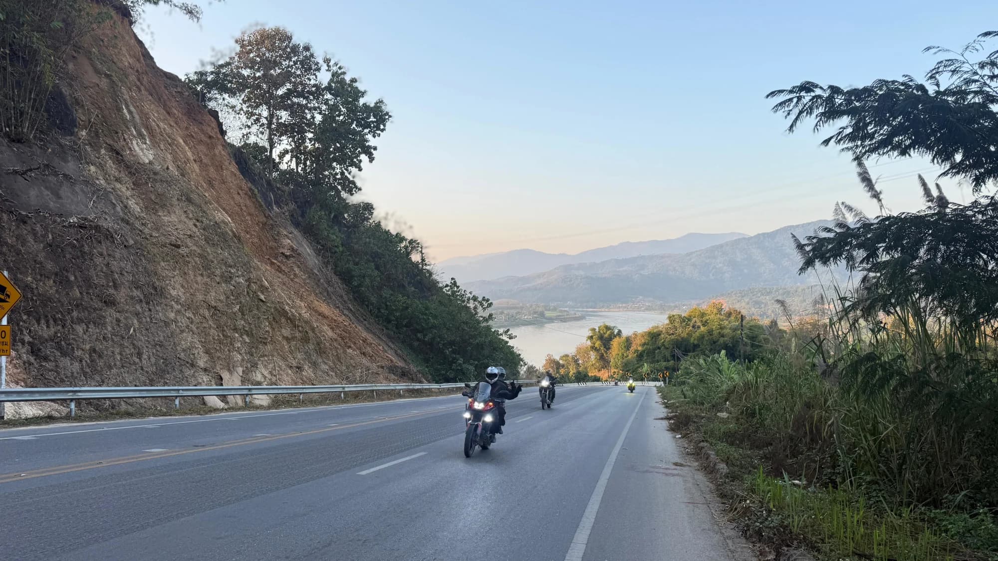 Rider signaling thumbs up coming up a mountain road
