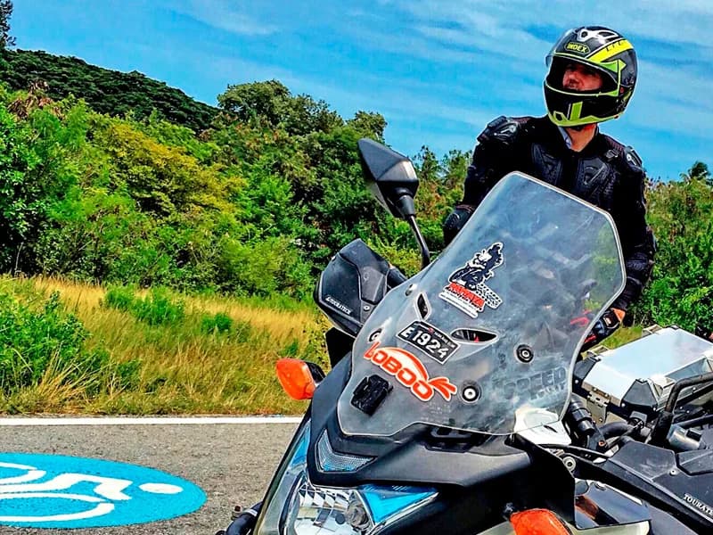Rider cruising on an open road with green hills