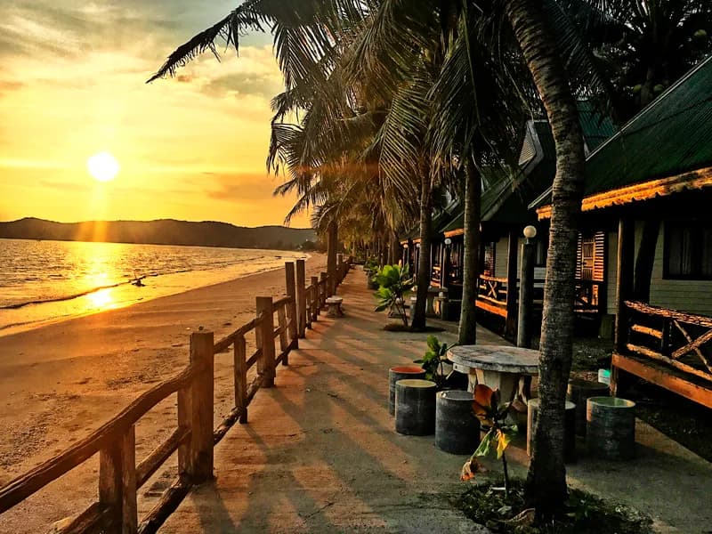 Golden sunset at beachfront accommodation with palm trees in Chanthaburi