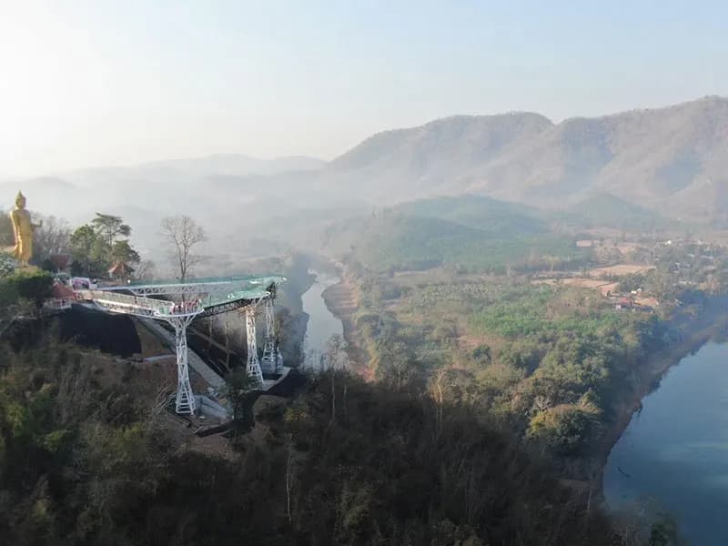 Mekong River glass-bottom skywalk with Buddha statue and misty mountains